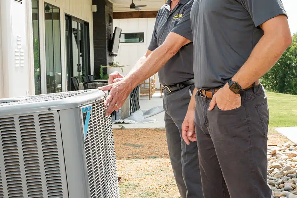 Two Frymire employees assessing a heat pump outside 