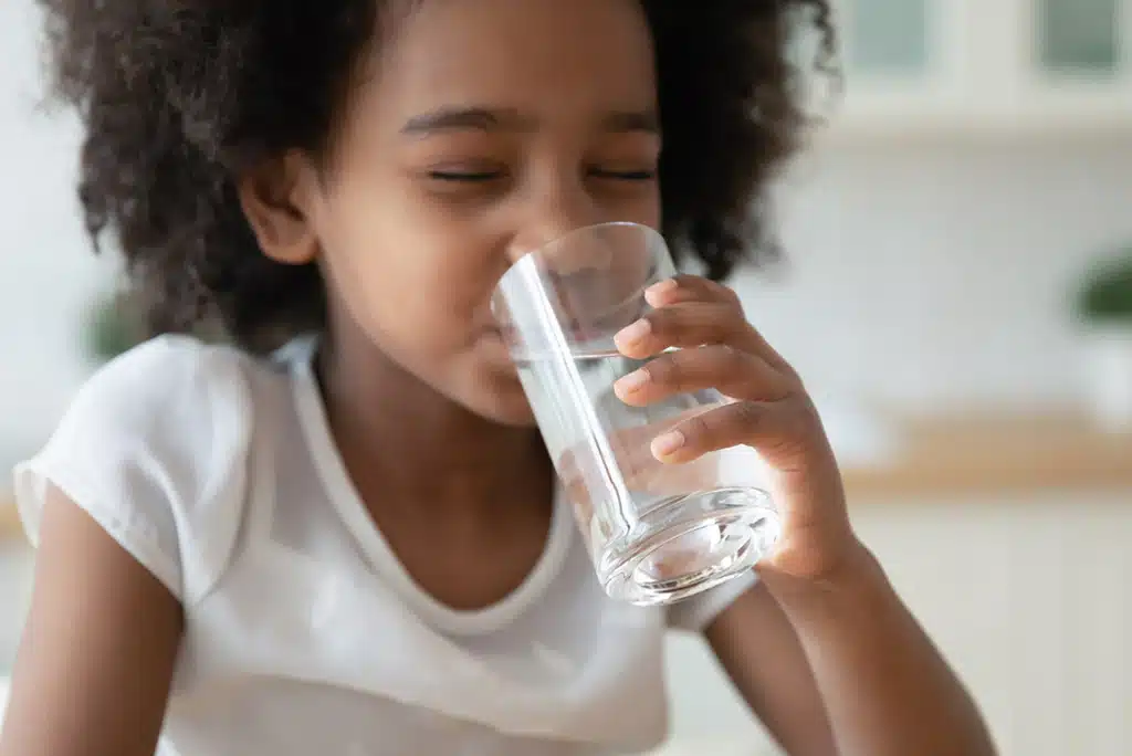  Child drinking a glass of clean water with filtration 