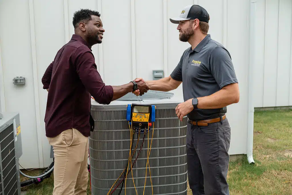  frymire hvac technician shaking hands by HVAC with a homeowner 