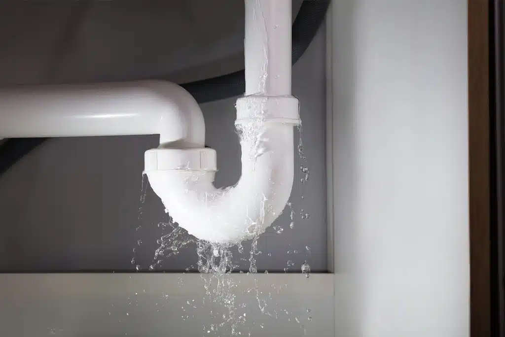 A white under-sink pipe leaking water